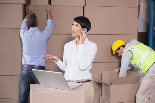 Warehouse manager using laptop and talking on phone