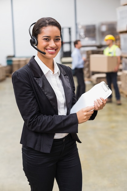 Warehouse manager wearing headset holding clipboard