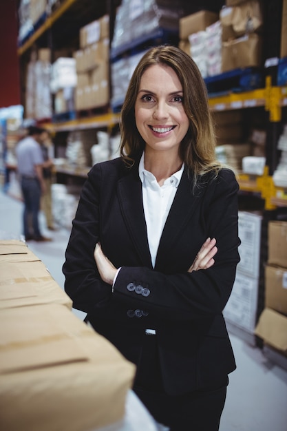 Warehouse manager with arms crossed smiling at the camera