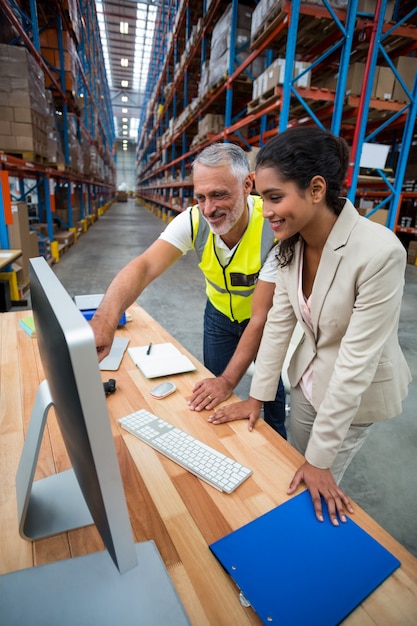 Photo warehouse manager and worker discussing with computer