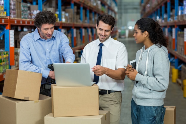 Warehouse manager and worker discussing with laptop