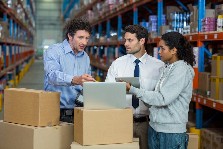 Photo warehouse manager and worker discussing with laptop