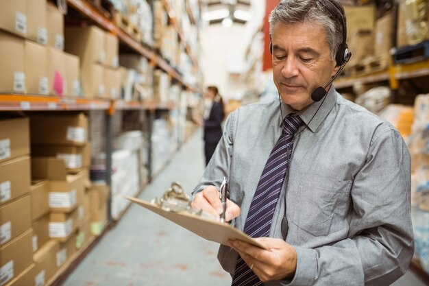 Warehouse manager writing on clipboard