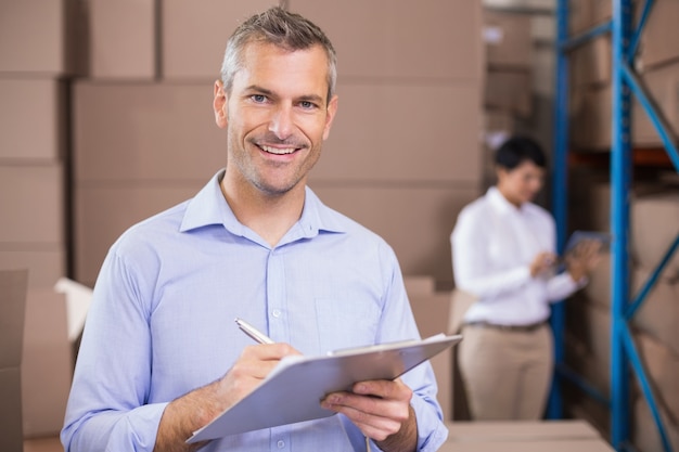 Warehouse manager writing on clipboard