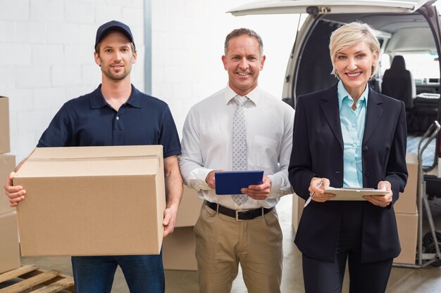 Warehouse managers and delivery driver smiling at camera