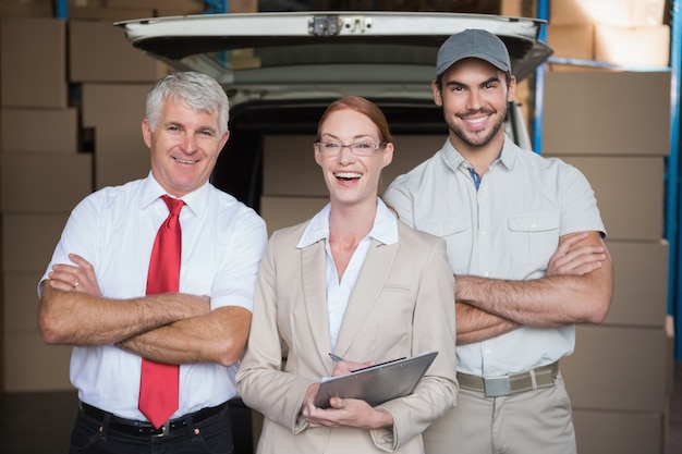 Warehouse managers and delivery driver smiling at camera