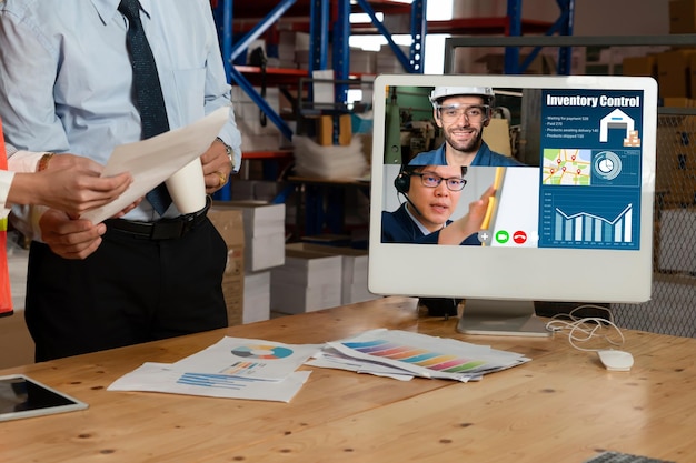 Warehouse staff talking on video call at computer screen in storage warehouse