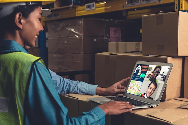 Warehouse staff talking on video call at computer screen in storage warehouse