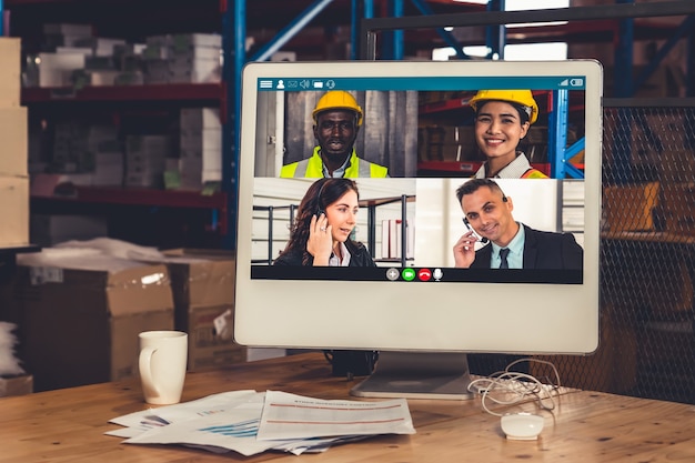 Warehouse staff talking on video call at computer screen in storage warehouse