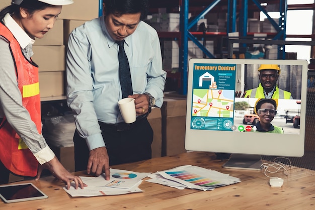 Warehouse staff talking on video call at computer screen in storage warehouse