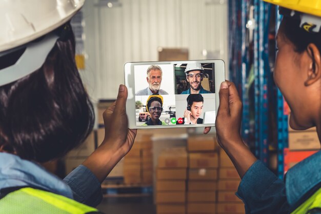 Warehouse staff talking on video call at computer screen in storage warehouse
