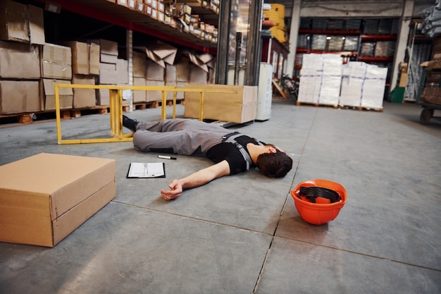 Premium Photo  Warehouse worker after an accident in the storage. Man in  uniform lying down on the ground.