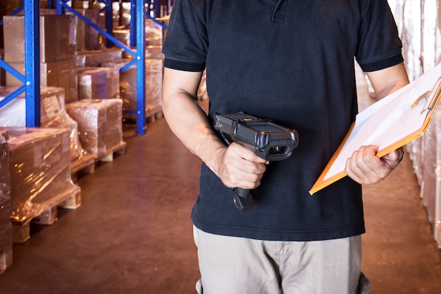 warehouse worker are holding barcode scanner and a clipboard working with inventory in warehouse store.