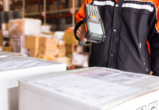 Warehouse worker are holding barcode scanner with scan laser on
a parcel boxes in warehouse distribution.