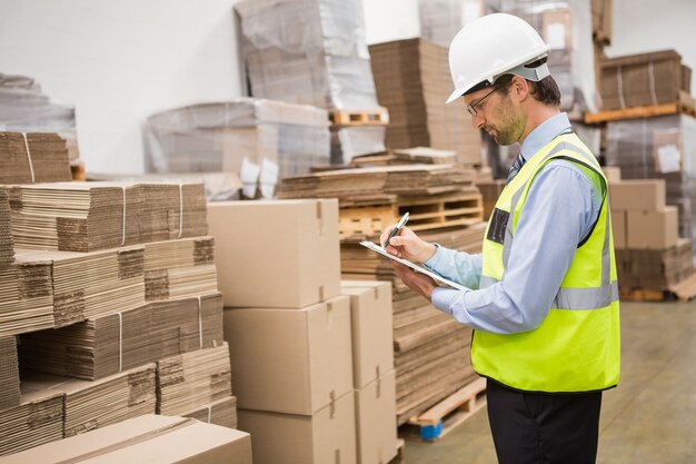 Warehouse worker checking his list on clipboard