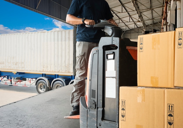 Photo warehouse worker driving forklift pallet jack unloading pallet goods