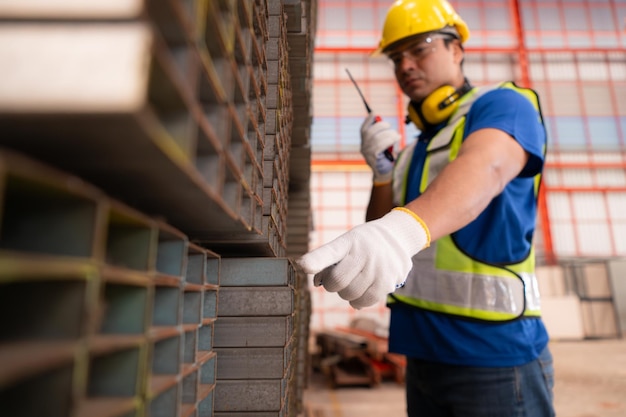 Warehouse worker in hard hats and helmets stand in the warehouse to count and inspect the steel