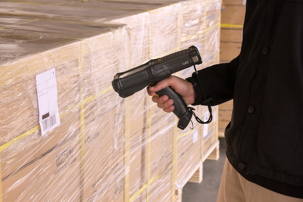  Warehouse worker holding barcode scanner with scanning on a pallet shipment.