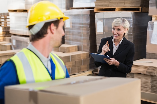 Warehouse worker holding box with manager behind him