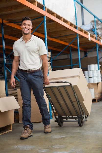 Warehouse worker moving boxes on trolley