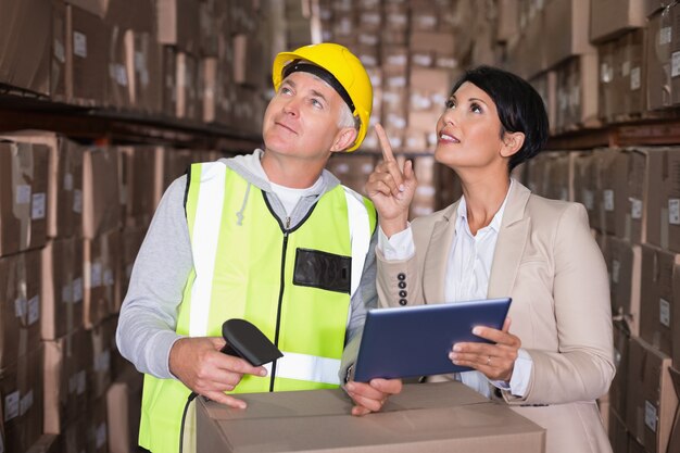 Warehouse worker scanning box with manager