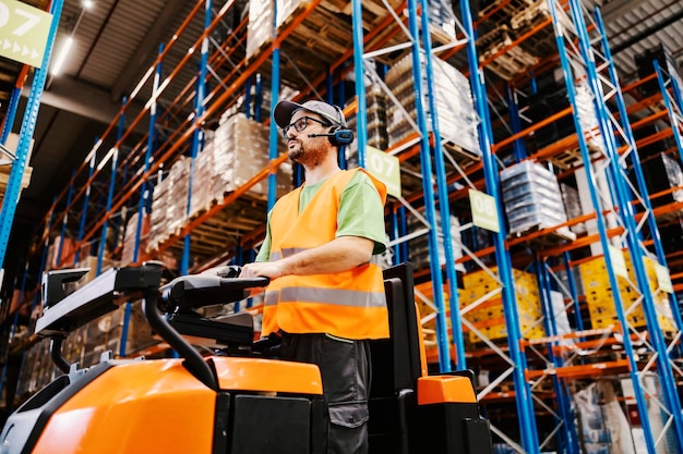 A warehouse worker with voice picking headset driving forklift