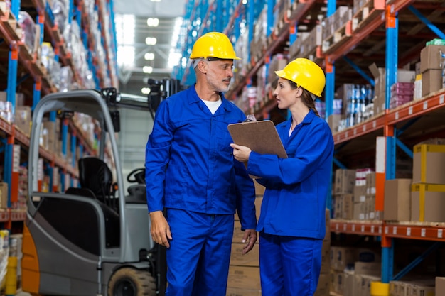 Warehouse workers discussing with clipboard