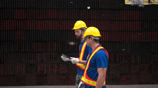 Warehouse workers in hard hats and helmets Inspect and count steel in the warehouse