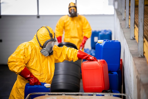 化学物質や酸を移動する保護防護服を着た倉庫作業員