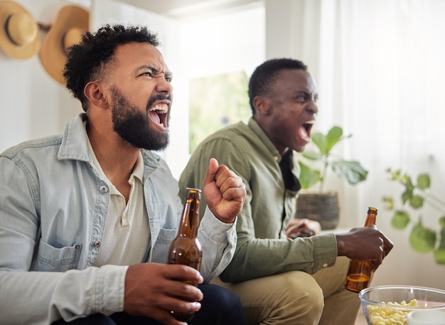 Waren deze aan het winnen. Shot van twee mannelijke vrienden die er vrolijk uitzien terwijl ze bier drinken en samen zitten.