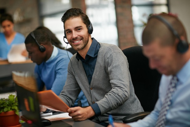 Waren hier om te helpen bijgesneden portret van een zakenman die met zijn collega's op kantoor werkt