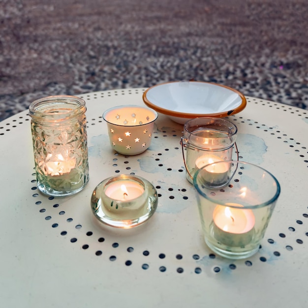 Теплые свечи в прозрачном стекле на столе на улице
