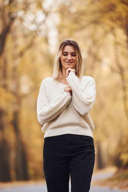 In warm clothes. Portrait of young brunette that is in autumn forest at daytime.