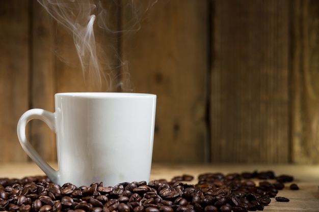 Warm cup of coffee on wooden table and coffee beans 