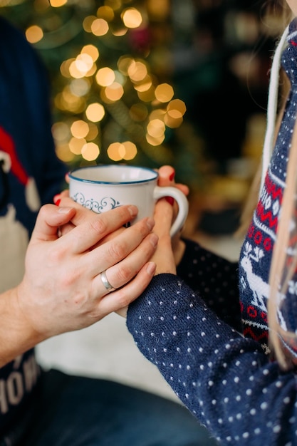 温かい飲み物のカップの手の愛好家のクリスマスの夜