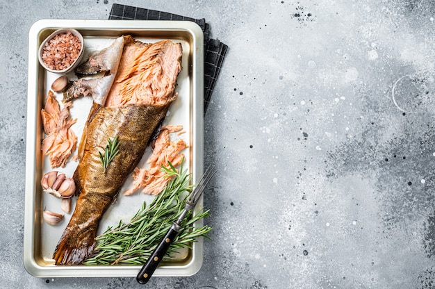 Warm gerookte zalm, forelvis met kruiden. Grijze achtergrond. Bovenaanzicht. Ruimte kopiëren.