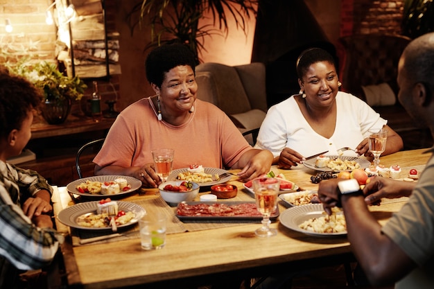 Warm getint portret van een gelukkige Afro-Amerikaanse familie die 's avonds samen binnen geniet van het diner