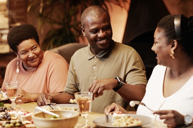 Warm getinte portret van een gelukkige Afro-Amerikaanse familie die 's avonds samen buiten geniet van het diner