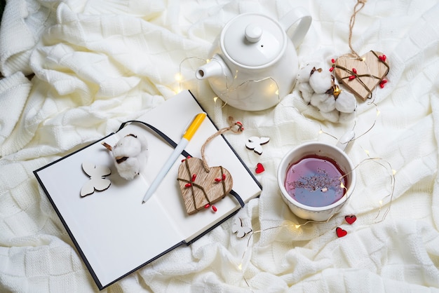 Warm knitted plaid,cup of hot tea and notebook