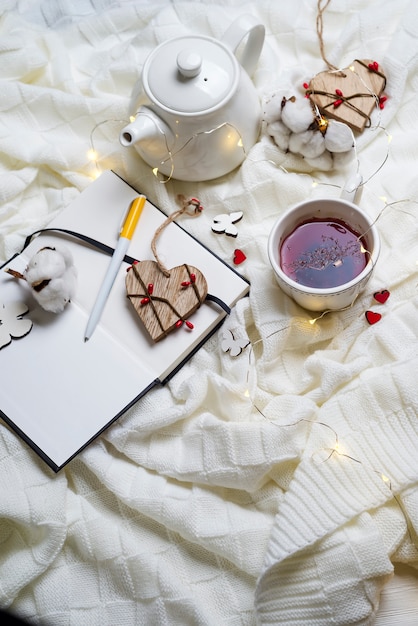 Warm knitted plaid,cup of hot tea and notebook