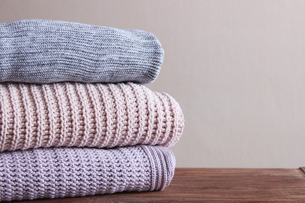 Warm knitted sweaters folded in a stack on a light background closeup