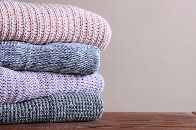 Warm knitted sweaters folded in a stack on a light background closeup