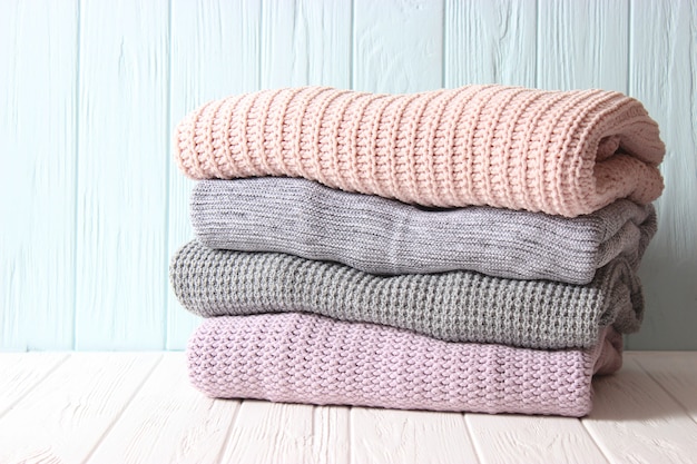 Warm knitted sweaters folded in a stack on a light background closeup