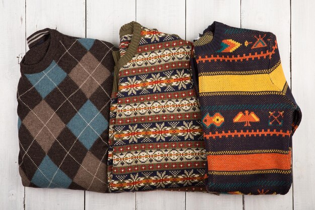 Warm knitted sweaters on a wooden shelf Set of winter pullovers with different ornament