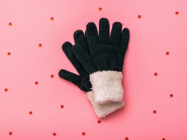 Теплые вязаные женские перчатки на розовом фоне с блестками. женские аксессуары для холода.