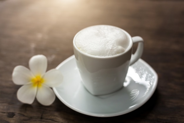 Warm kopje zwarte koffie met witte bloem decor op tafel