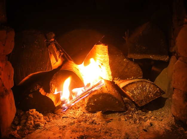 Warm licht van een brandend helder vuur in een open haard in een oude Russische kachel. Vlam en brandhout achtergrond. Detail van het interieur.