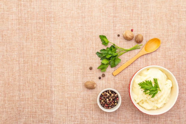 Warm mashed potatoes in a ceramic bowl with fresh parsley and dry spices and herbs