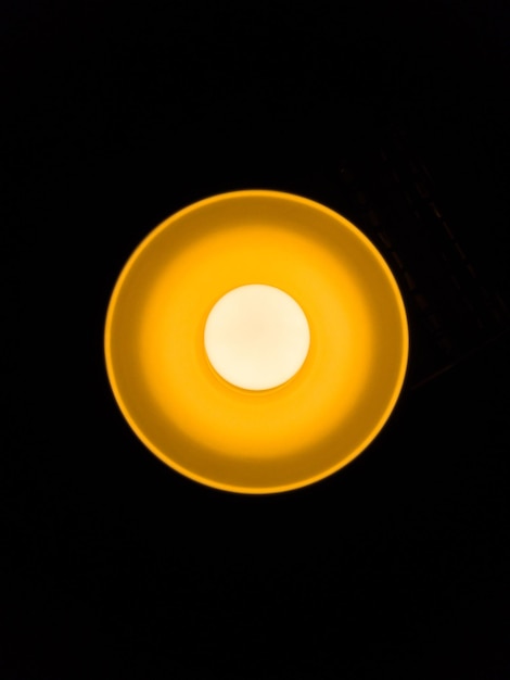 Photo warm orange led lamp in the ceiling on a dark background in the center of the frame bottom view