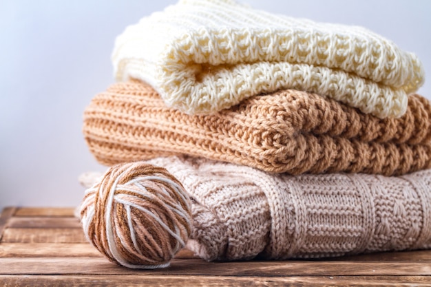 Warm, pastel clothes, knitted, pastel-colored scarves and a\
ball of knitting yarn winter, autumn clothes.